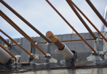 Metal rebar protruding from the end of a concrete beam.
