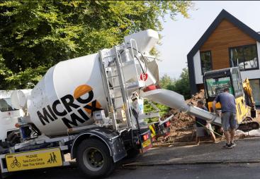 Two men unload concrete from one of Micromix’s agile trucks, which can deliver concrete loads from 0.5 to 4 m³, now with added convenience via online ordering.