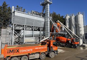 An orange tipper truck and orange cement mixer wait by the new iMIX plant in Essex is MCT Italy’s first UK ready-mix installation, built for high-volume output and flexibility.
