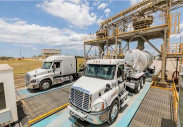 Two US trucks load up with materials at Eco Material Technologies, which supplies supplementary cementitious materials, critical for reducing embodied carbon in concrete.