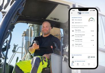 A PPE clad construction worker sits in a machine cab holding a mobile, with a screen shot of the mobile using Kleemann’s SPECTIVE CONNECT app, which now enables remote control and monitoring of crushing and screening equipment, on the right of the picture.