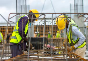 Two men in PPE working on rebar on a construction site