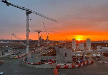 Sunrise over the construction of Old Oak Common Station in London, one of several HS2 sites supplied by Holcim UK, with a tower silhouetted against a setting sun