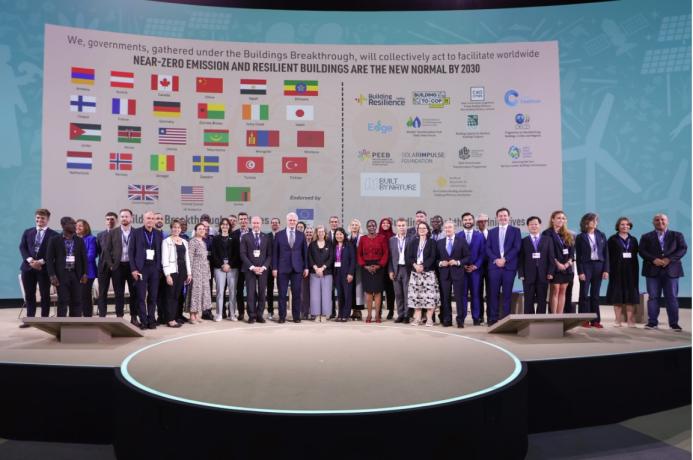 Lots of people standing on a podium with their countries flags in the background following the launch of the UAE and Canada's Breakthrough Initiative at COp28