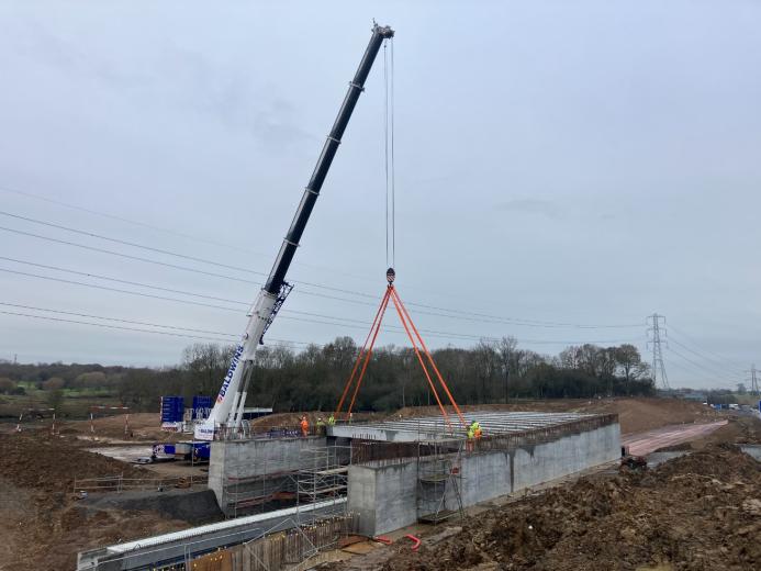 A crane lifting concrete beams to construct a road bridge