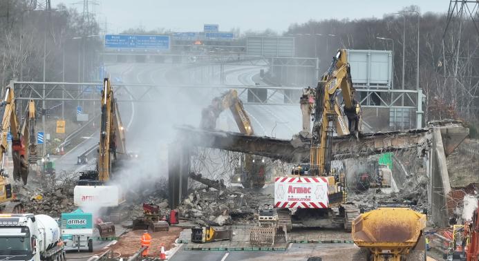 A motorway bridge being demolished using several large excavators