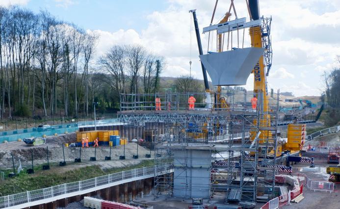 A concrete Y shaped block being lifted by a crane for a new railway viaduct