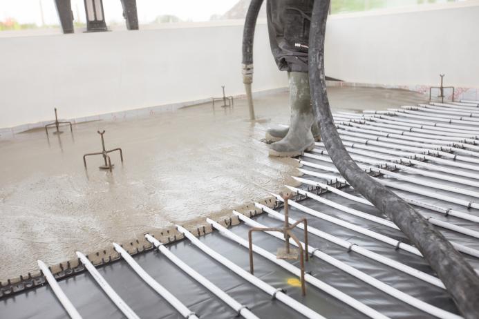 A picture of a man's legs and a concrete floor being screeded