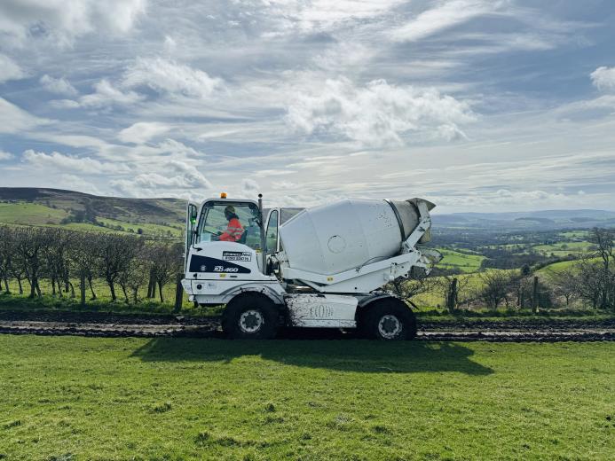 A white mobile concrete mixer in a green field