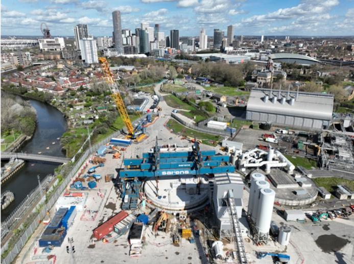 An aerial shot of a construction site with a yellow crawler crane and a large blue gantry crane