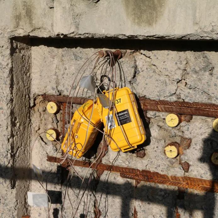 yellow boxes with lots of wires hanging on a newly poured concrete wall