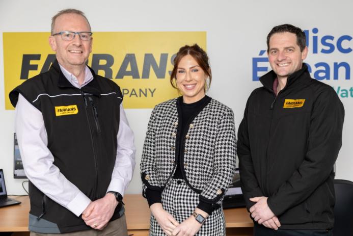 Three people, two men and a woman, standing with their hands clasped, looking at the camera