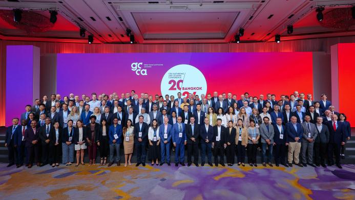 A large group of people standing infront of a white round sign and red lighting