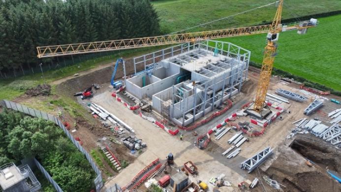 Aerial view of an under construction waste water treatment works with a yellow tower crane