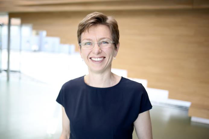 A head and shoulders photo of a woman with short hair, glasses and wearing a black tshirt