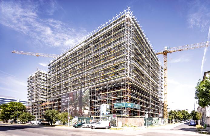 An under construction mid-rise building covered in scaffolding