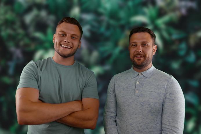 Two men grinning at the camera, one in short sleeves, the other in long sleeves