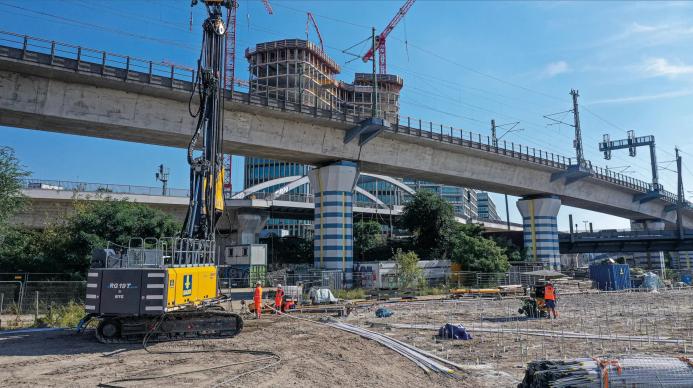 A yellow piling rig stands in front of a bridge on a construction site in Germany