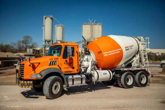 A bright orange concrete mixer truck at a cement plant