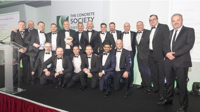 Lots of men in a line wearing black tie celebrate winning the Concrete Society’s annual Awards for Excellence in Concrete 2024 at The Royal Lancaster London