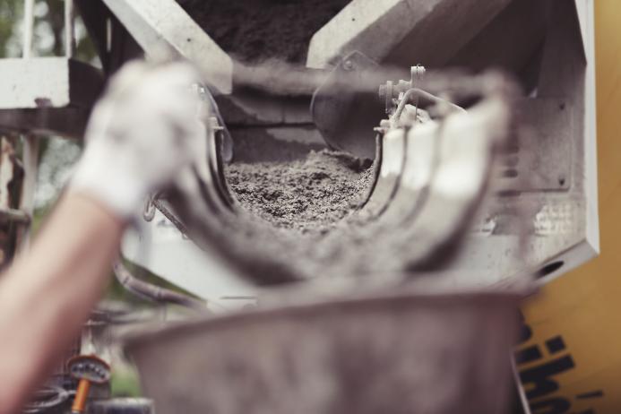 Concrete being poured from a mixer into a container. A dynamic action image shows wet concrete being dispensed from a mixer into a container, capturing the essence of construction work and the creation of solid foundations in building projects.