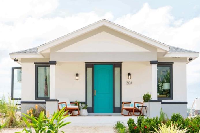 A white, single storey house with a green door