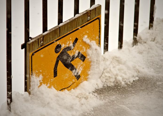 A health and safety sign of a person slipping on ice, covered in snow