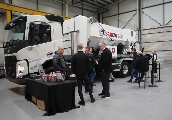 A group of men socialize in front of a volumetric concrete mixer at Volumetric's first Christmas open day was held at its new facility in Wednesbury, in the West Midlands. 