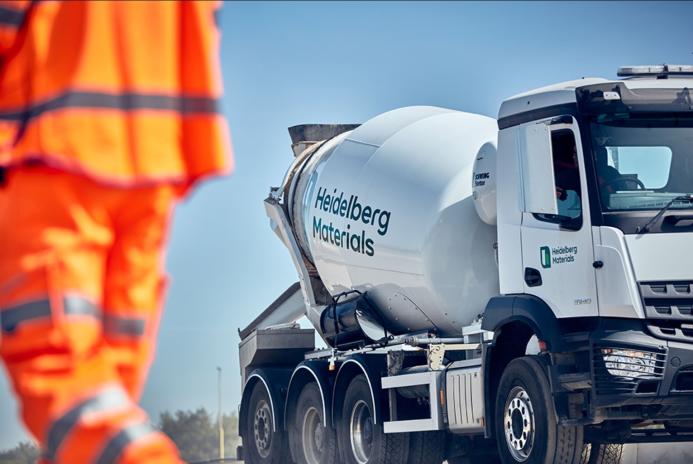 A man in orange PPE and a Heidelberg Materials concrete truck mixer