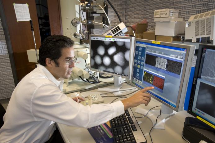 A man in lab clothes looking at monitors in a laboratory