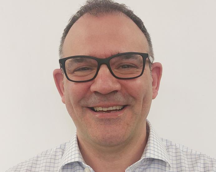 Head and shoulders picture of a smiling man in glasses