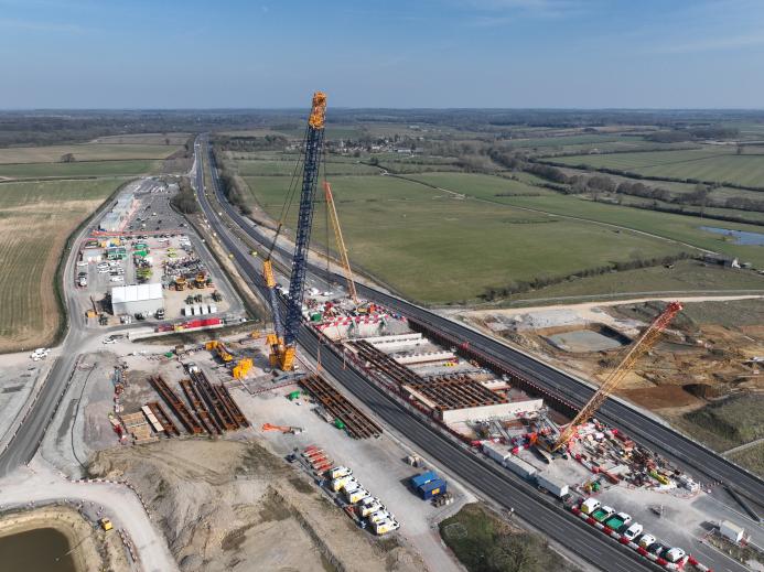 An aerial view of three cranes as the prepare to install bridge beam on the A43 for HS2, March 2025.