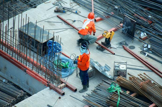 Two PPE clad construction workers install rebar ties