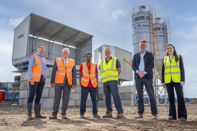 L–R: Prof. David Hughes; Bob Borthwick; Scott Bros recycling innovation engineer Feysal Shifa; Peter Scott; Joss Newberry; and Cassidy Smith, Teesside University’s IP and commercialization manager, standing in front of Scott Brothers new low-carbon concrete plant in Teeside.
