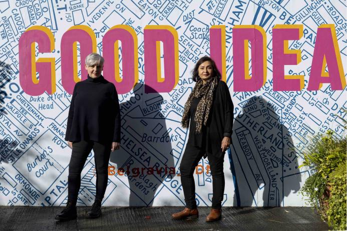 Ruth Sparkes and Sunita Gordon, co-founders of SaferSpace, dressed in black, photographed in harsh sunlight against a map of London with the slogan "Good Idea" printed over it.