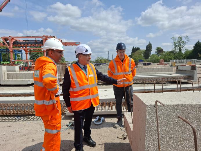 Three men in PPE, including Councillor Tony Eaton, chairman of Bassetlaw District Council, examine precast concrete elements in ABM Precast Solutions' yard during the company's 20th Anniversay celebrations.