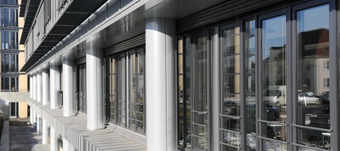 A glass fronted office with concrete columns.