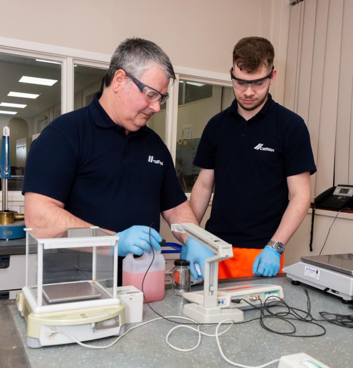 Two men in black and safety goggles working on Cemex’s Prime admixtures in its lab 