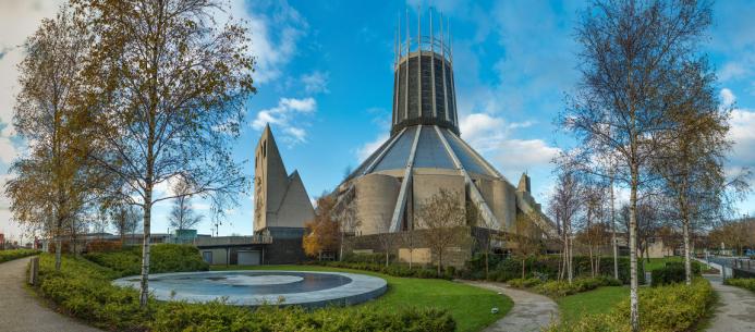 A view of Liverpool Metropolitan Cathedral in early summer with trees and a pond