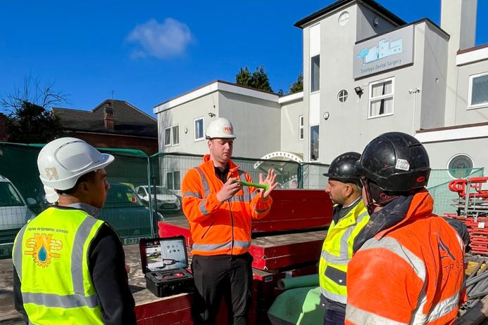 Men in a variety of PPE in front of a dental surgery discuss PERI UK and SWS's integrated waterproofing and formwork solution