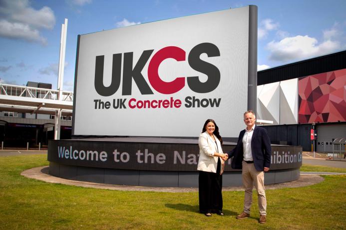 Richard Bradbury (right), Managing Director of The QMJ Group with Helaena Ackers, Exhibition Sales Account Manager, The NEC shake hands outside the NEC in front of a huge UK Concrete Show sign, following the signing of a two-year deal that sees the flagship trade show to stay at Birmingham’s NEC through 2027, with free parking and expanded plans for 2026 edition