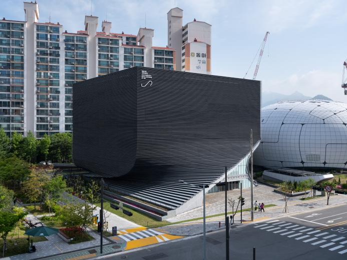 An exterior view of the Photography Seoul Museum of Art (Photo SeMA) features a distinctive twisted silhouette, created using a rhythmic layering of angled precast concrete panels.