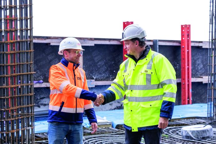 Two men in PPE shake hands - Close cooperation between PERI and Porr AG underpins the tower’s vertical progress. (All photos: PERI SE)