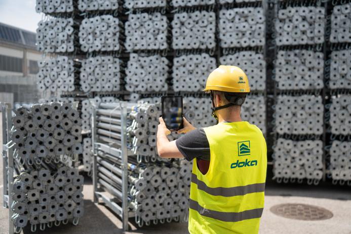 A man in Doka branded PPE uses an AI device to count formwork elements