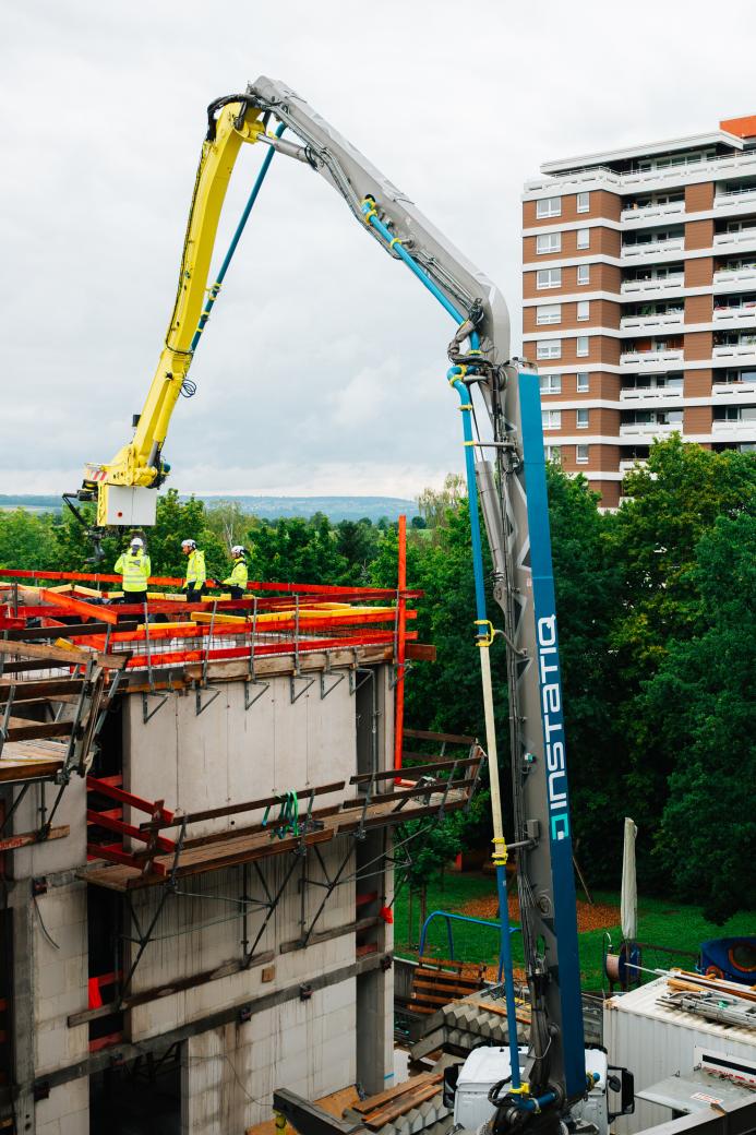 A concrete pump delivers concrete to the top floor of an under construction mid-rise building
