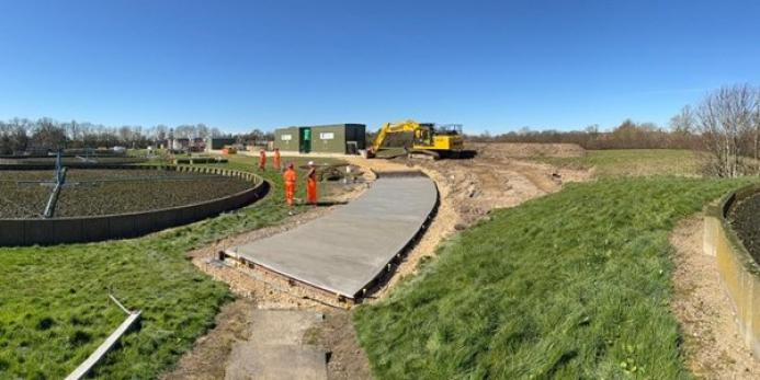 A waste water treatment plant with a CoMLaG mix access road in the foreground surrounded by grassy banks