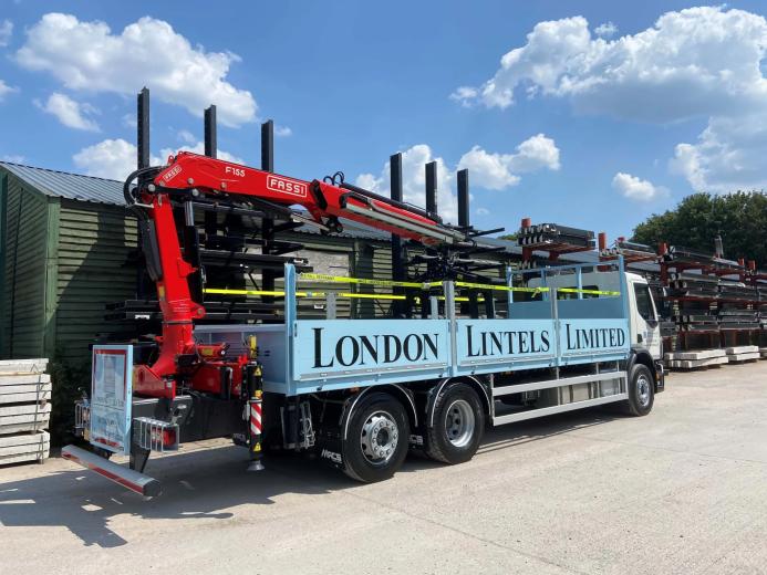A blue London Lintels liveried truck with red loader crane mounted at the rear in London Lintels yard. London Lintels, now part of the Milbank Group, distributes concrete and steel lintels to customers across London and the South.