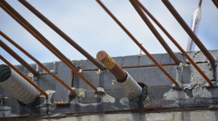 Metal rebar protruding from the end of a concrete beam.
