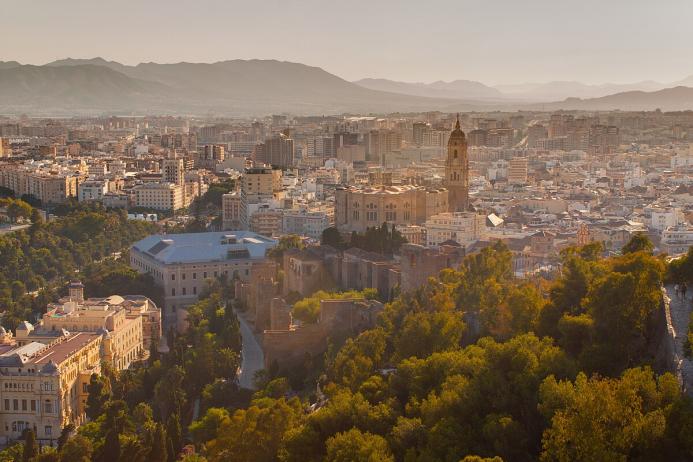 A panoramic photo of Malaga city centre with mountains in the distance, with the bullring lower right and a large church middle left.