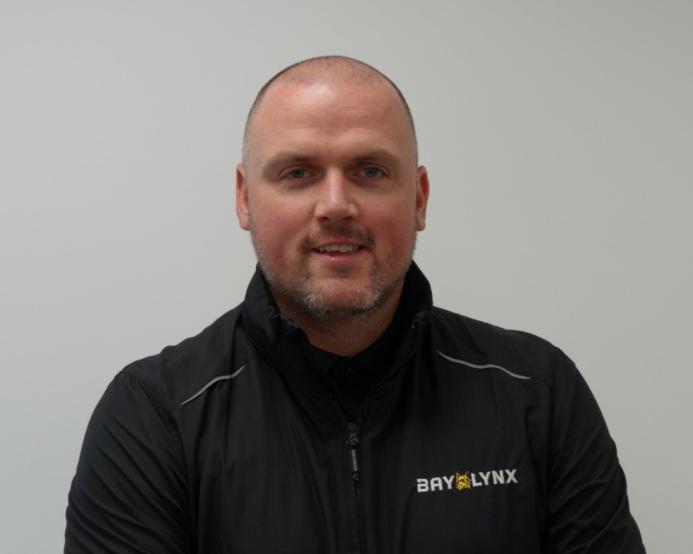 A bald man in a black fleece branded with the Bay-Lynx logo.
